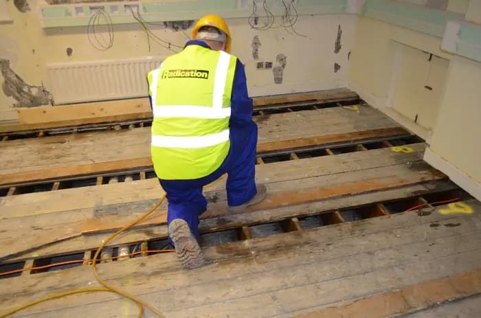 Radication technician lifting floorboards to treat woodworm